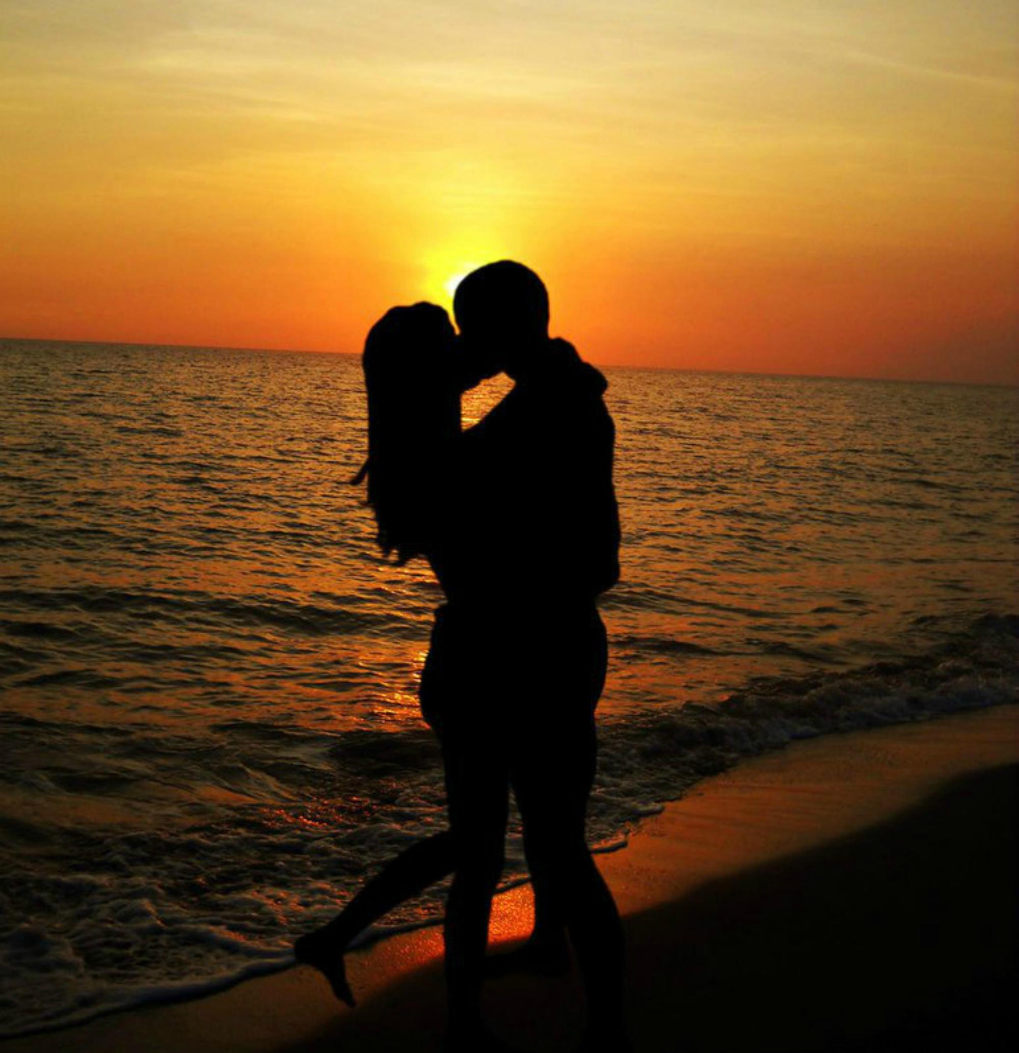 Влюбленная пара на берегу моря на закате