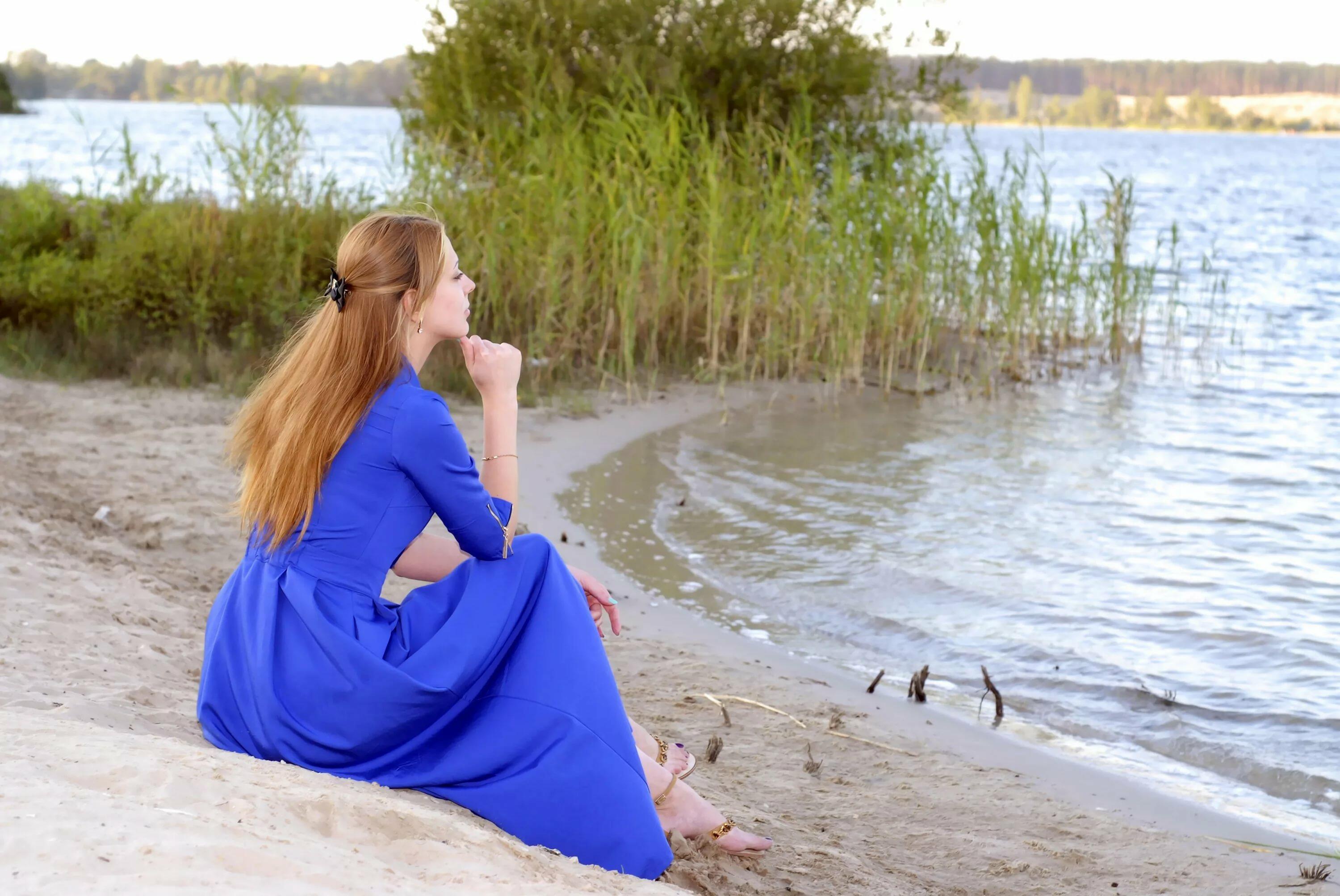 Песня на другом берегу реки. Девушка у реки. Женщина на берегу реки. Женщина сидит на берегу реки. Женщина в платье у реки.